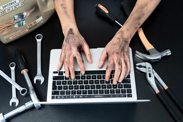Agentur für Webdesign - Website Service - SPITZBUB Braunschweig. Webentwickler. Dieses Bild zeigt schmutzige Hände an einem Laptop mit Werkzeugen