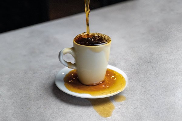 Webdesign & SEO - Was ist Keyword Stuffing? - Die Definition. Dieses Bild zeigt eine Kaffeetasse, die überläuft